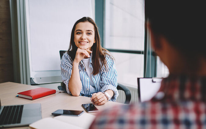 Logout Lehrstellenportal Logout Lehrstellenportal – Junge Frau sitzt lächelnd am Schreibtisch