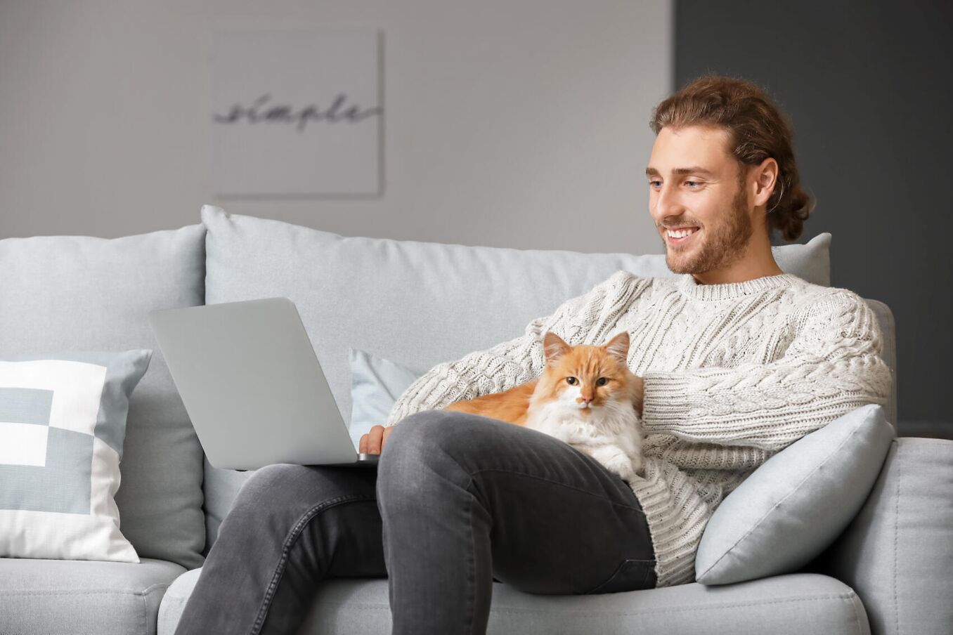 Kontakt – Mann sitzt mit Katze und Laptop auf Sofa