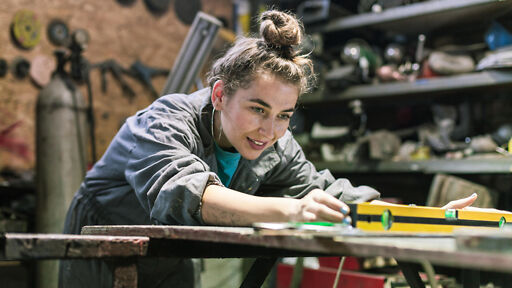 Junge Frau in der Werkstatt im Rahmen ihrer Metalldesign Lehre Junge Frau in der Werkstatt im Rahmen ihrer Metalldesign Lehre