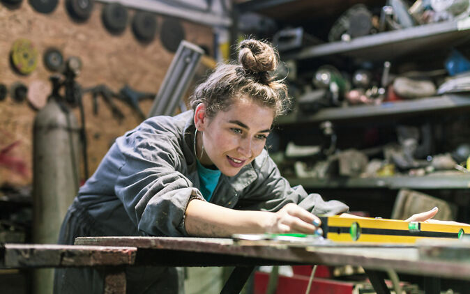 Junge Frau in der Werkstatt im Rahmen ihrer Metalldesign Lehre Junge Frau in der Werkstatt im Rahmen ihrer Metalldesign Lehre