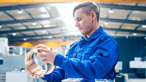 Junger Mann arbeitet mit Maschine in seiner Metallbearbeitung Lehre Junger Mann arbeitet mit Maschine in seiner Metallbearbeitung Lehre