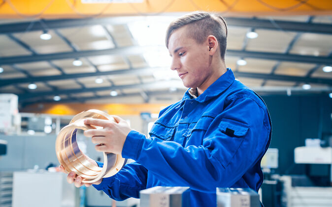 Junger Mann arbeitet mit Maschine in seiner Metallbearbeitung Lehre Junger Mann arbeitet mit Maschine in seiner Metallbearbeitung Lehre